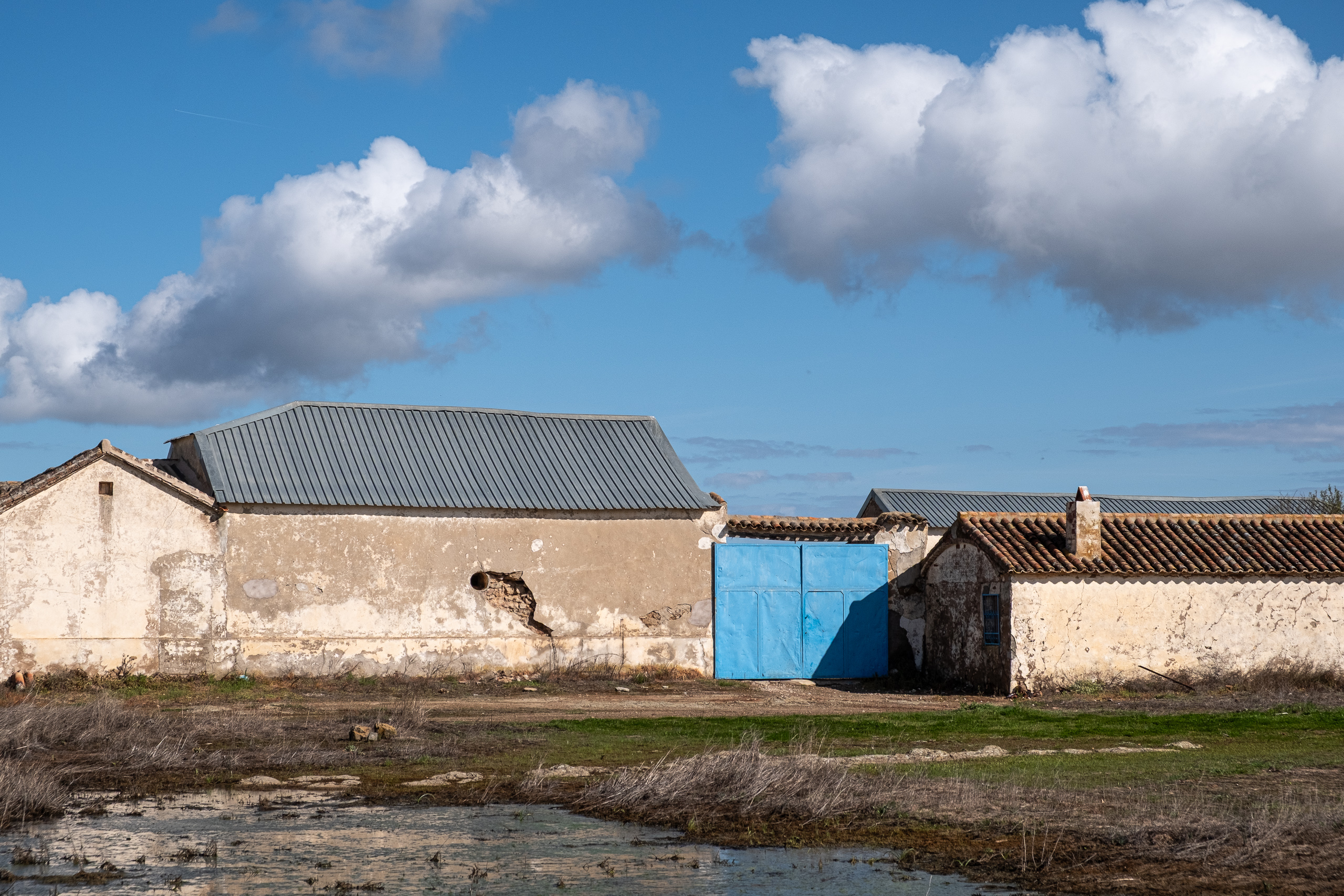 Verfallener Hof mit blauer Tür an der Strecke